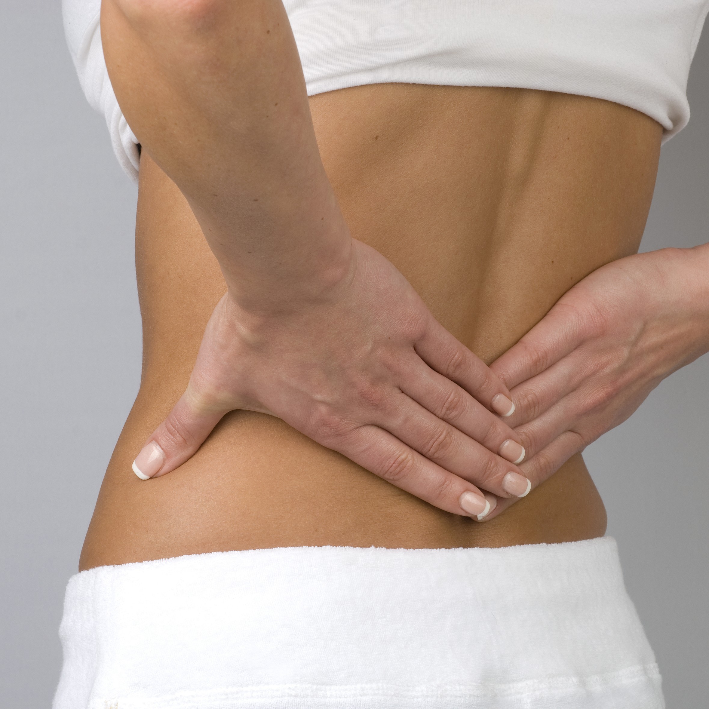 Woman's hands pressing against her lower back suggesting pain.